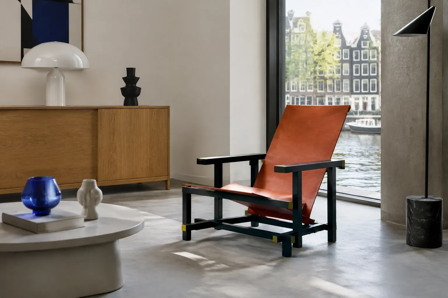 Lage leren fauteuil met zwarte houten frame in licht minimalistisch interieur aan grachtzijde